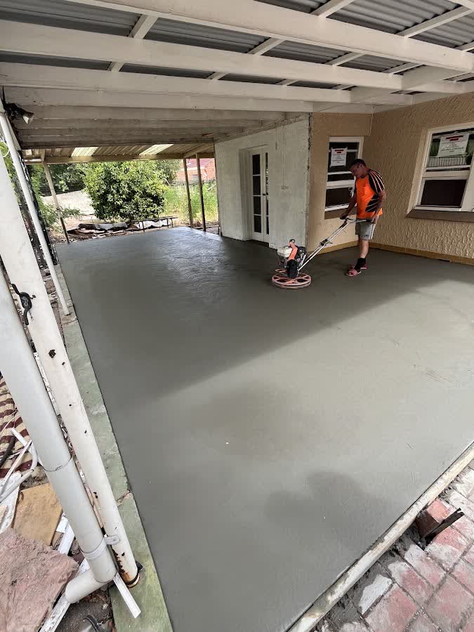 A tradesman power-trowelling a fresh concrete carport slab to a smooth finish