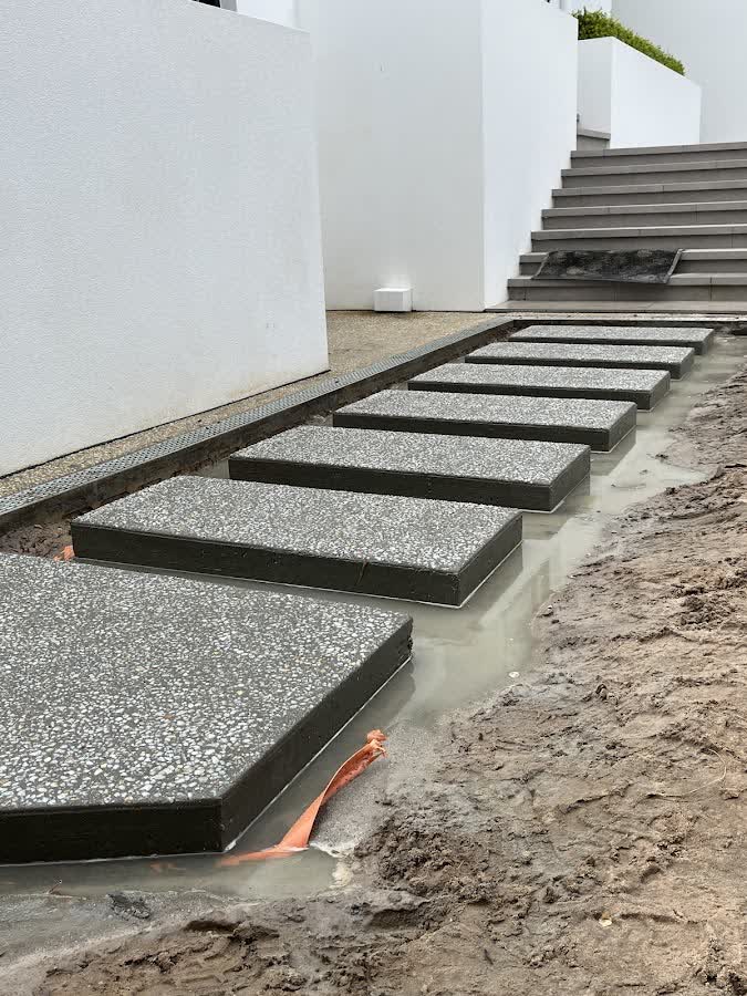 Premium exposed-aggregate stepping-stone pavers being set beside rendered steps